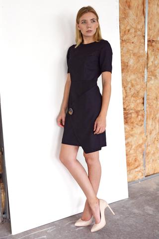 The Flap Front Dress is a Black Sheath dress with elbow length sleeves and a front wrap around flap. Made in 100% wool. Fully lined.